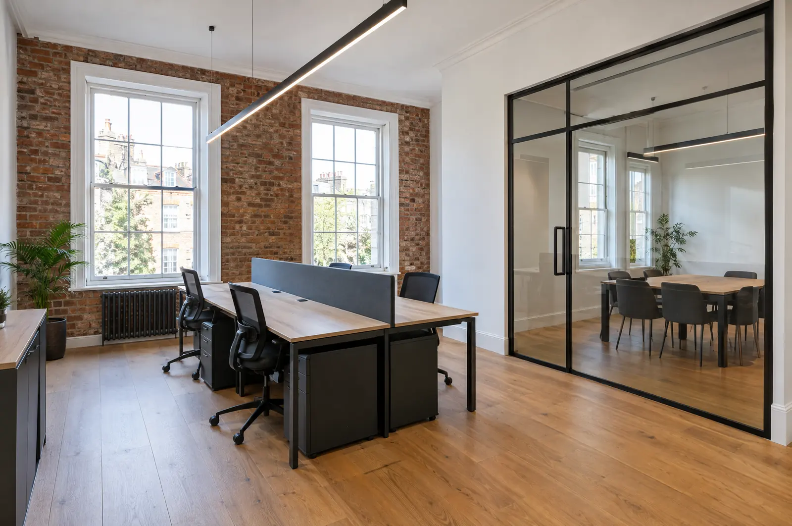 A refurbished office with exposed brick, sash windows and a glass meeting room